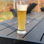 Glas med Sommer i Tyrol hvedeøl med tæt hvidt skum på et havebord