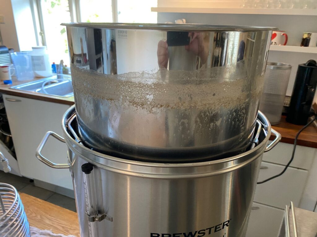 Maltkurv løftet op over brygkedlen, så urten kan dryppe af efter mæskningen